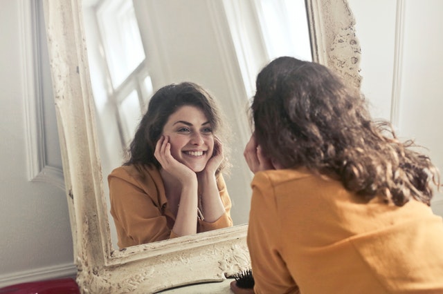 Vrouw kijkt lachend in de spiegel en vindt zichzelf weer terug.