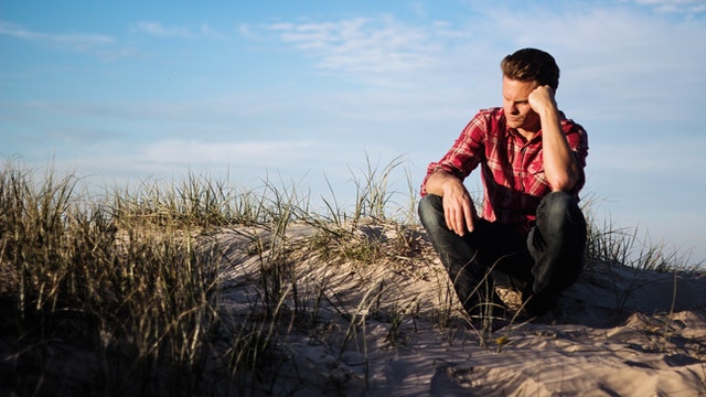 Man zit in de natuur en denkt na over zijn gevoelens na de relatiebreuk.
